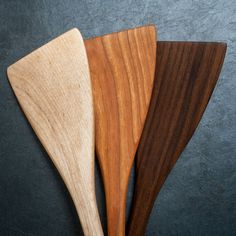 three wooden spoons sitting next to each other on top of a black countertop