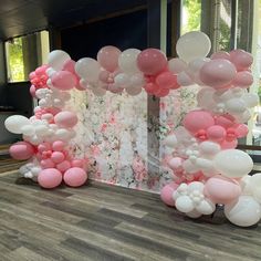 the balloon arch is decorated with pink and white balloons