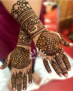 two hands with henna tattoos on them, one is showing the intricate design and the other has flowers