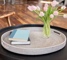 a glass vase filled with pink tulips sitting on top of a round table