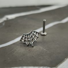 a pair of earrings sitting on top of a piece of paper next to a screw