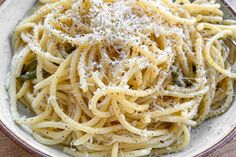 a white bowl filled with pasta and parmesan cheese on top of a wooden table