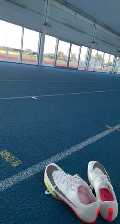 a pair of tennis shoes sitting on the floor in an indoor sports facility with windows