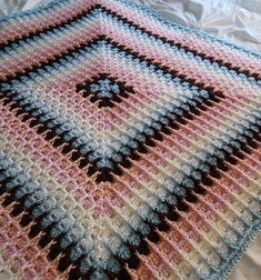 a crocheted blanket is laying on a bed