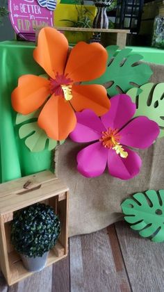 some paper flowers sitting on top of a wooden table next to a potted plant