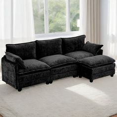 a black couch sitting on top of a white rug in front of a large window