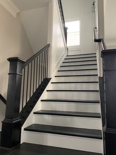 there is a black and white stair case next to the door on the stairs in this house