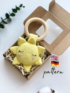 a small yellow stuffed animal in a cardboard box next to cotton balls and a plant