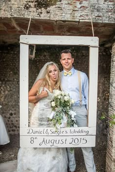 a bride and groom posing for a photo in front of an old frame that says, danielle & steve's wedding 8 august 2015