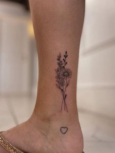 a woman's foot with a flower and heart tattoo on her left side ankle