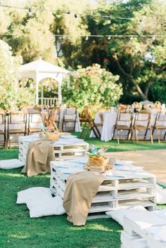 tables set up in the grass with white linens and wooden crates for seating on them