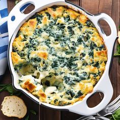 spinach and cheese casserole in a white dish with bread on the side