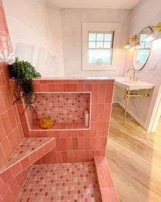 a bathroom with pink tiles on the walls and floor, along with a plant in the corner