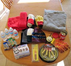 the table is covered with various items to pack for an adventure or camping trip, including socks, gloves, water bottles and other things