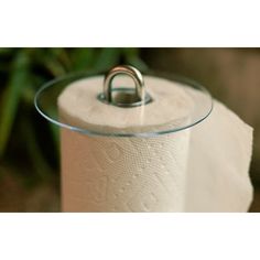 a roll of toilet paper sitting on top of a glass holder with a metal ring