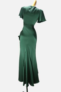 a green dress on a mannequin with a gold headpiece in the background