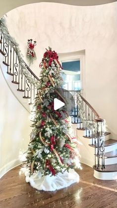 a decorated christmas tree sitting in the middle of a room next to a stair case