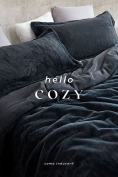 an image of a bed with black linens on it and the words hello cozy written in white