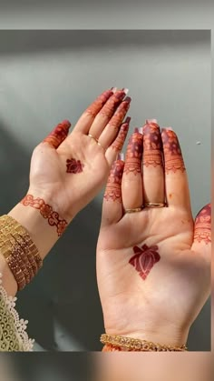 two hands with hendi tattoos on their palms, one holding the other's hand