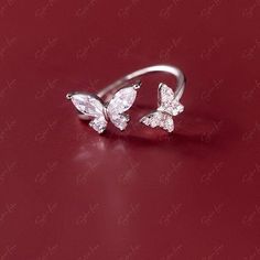 Capture the hearts of your loved ones with this stunning 925 sterling silver ring adorned with sparkling cubic zirconia gemstones in the shape of two delicate butterflies. Its open band design allows for easy adjustment to fit any finger size. Whether given as a gift or worn as an everyday accessory, this ring is sure to make a dazzling statement. Adjustable up to size US 6.Material: 925 sterling silver, cubic zirconiaFinish: platinum plate Jewelry Care: See more information about how to care fo Adjustable Butterfly Ring With Cubic Zirconia, Adjustable Cubic Zirconia Butterfly Open Ring, Adjustable Cubic Zirconia Butterfly Ring For Wedding, Adjustable Cubic Zirconia Butterfly Wedding Ring, Cubic Zirconia Butterfly Ring For Wedding, Cubic Zirconia Butterfly Open Ring For Promise, Cubic Zirconia Open Butterfly Ring For Promise, Cubic Zirconia Open Butterfly Ring For Anniversary, Butterfly Ring With Cubic Zirconia As A Gift