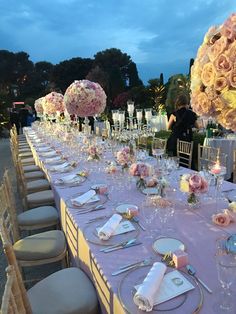 a long table is set up with flowers and candles for an elegant wedding reception at dusk