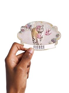 a hand holding up a sticker with a tiger on it's back and the words fierce in front