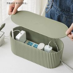 a person is holding an electrical device in a storage container on the table next to a cactus