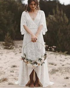 a woman in a white dress holding a flower wreath