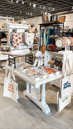 there are many bags on the table in this store that is selling clothing and other items