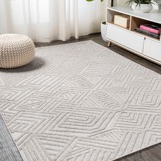 a white rug with an intricate design on the floor in front of a large window