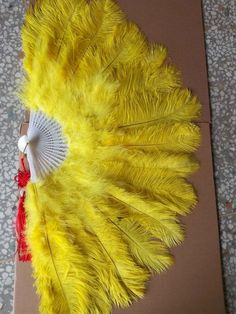 a yellow feather fan sitting on top of a cardboard box