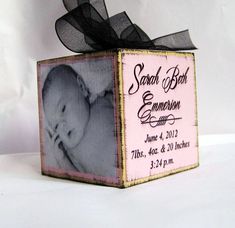 a baby announcement box with a black ribbon on top and a photo in the middle