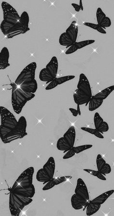 many black butterflies flying in the sky with snow flakes on them and sparkles all around