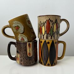 three coffee mugs sitting side by side on a table