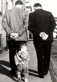 two men and a little boy walking down the sidewalk