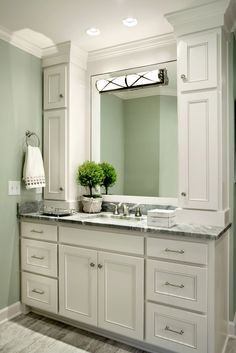 a large bathroom with white cabinets and marble counter tops, along with a green wall