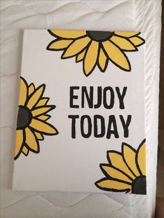 a white and yellow sign with sunflowers on it that says enjoy today in black lettering