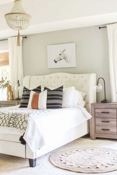 a white bed sitting in a bedroom on top of a wooden dresser next to a window