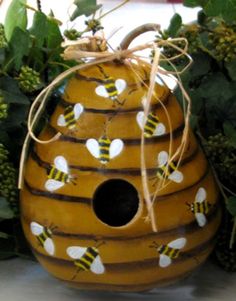 a beehive shaped planter with bees painted on it and tied to the side