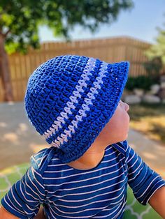 a child wearing a blue hat with white stripes on it and the text, sun & sand bucket hat for kids free crochet pattern