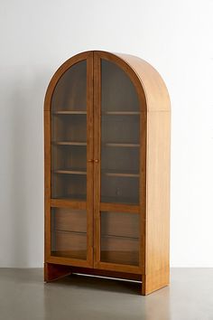 a wooden display case with glass doors on the top and bottom shelves, in front of a white wall