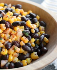 a wooden bowl filled with corn and black beans