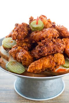 fried chicken and pickles on a bun in a metal bowl with a candle sticking out of it