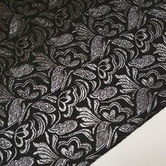 an image of a black and white lace fabric with flowers on it's side