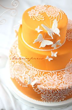 an orange wedding cake with white butterflies on it