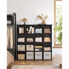 an organized closet with clothes, bags and other items on shelves in front of a window