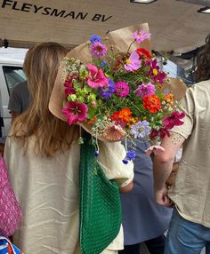 a woman holding a bouquet of colorful flowers