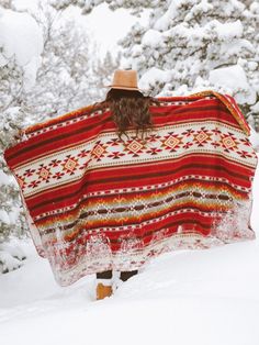 a woman is walking in the snow with a blanket