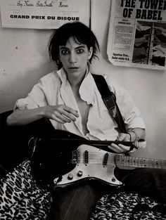 a woman sitting on top of a bed holding an electric guitar in front of her face