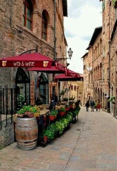 an alley way with several planters on the side and people walking down the street